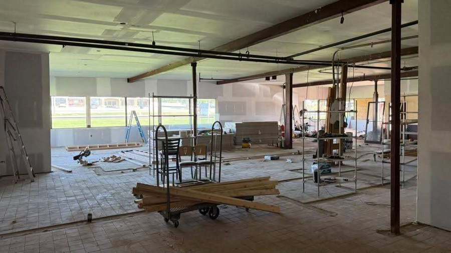 Commercial interior under construction with drywall, ladders and materials
